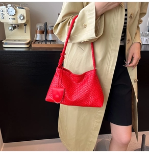 Detail of red woven leather shoulder bag with thick strap and matching tassel charm
