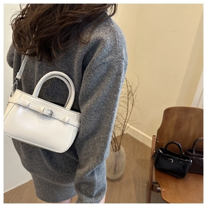 Photo lifestyle d'un sac bandoulière en cuir blanc montrant son profil élégant sur un mannequin