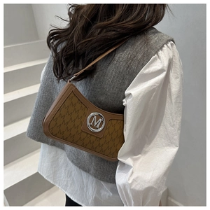 Close-up of brown underarm bag with M-letter monogram print and silver metal logo