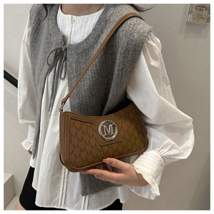 Close-up of brown shoulder bag featuring M-letter monogram and metallic logo detail