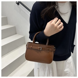 Détail d'un sac à main en cuir marron foncé avec boucle vintage et poignée ronde