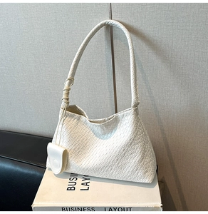 Detail of white woven texture shoulder bag with small pouch and cord-wrapped strap