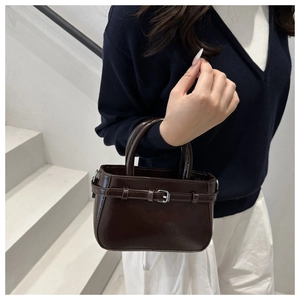Détail d'un mini sac à main en cuir marron brillant avec une boucle métallique décorative