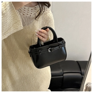 Detail of a black mini handbag with smooth faux leather finish and silver buckle strap