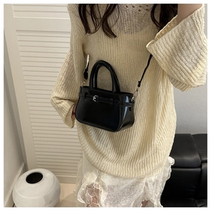 Classic black leather-look crossbody bag styled with trendy outfit in minimalist interior