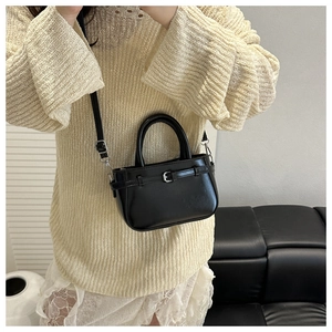 Bolso de mano negro mini a la moda con hebilla plateada y correa ajustable llevado por modelo