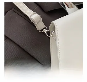 Close-up of white leather shoulder strap with silver metal buckle and adjustable clasp