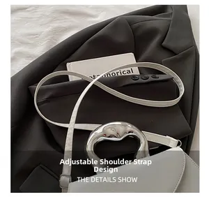 Detail of adjustable shoulder strap and silver metal handle on white leather handbag