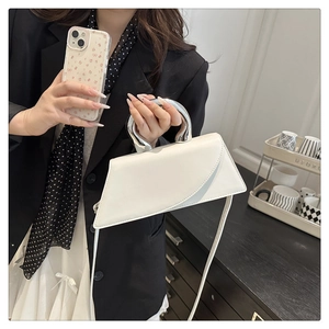 Detail view of stylish white leather geometric handbag with shiny silver metal handles