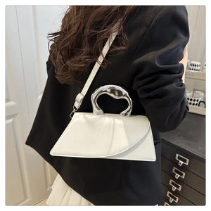 Close-up of a white leather bag with a unique silver organic metal handle and strap