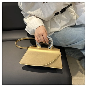 Modern gold satin handbag featuring a curved silver metal handle and asymmetrical shape