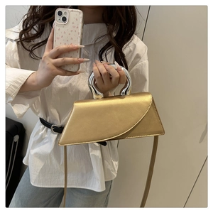 Detail of irregular geometric gold silk bag with silver circular metal handle and strap