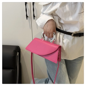 Detailed view of pink asymmetrical leather handbag with metallic silver handle and strap
