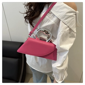 Detail of rose pink trapezoid handbag with silver metal handle and leather texture