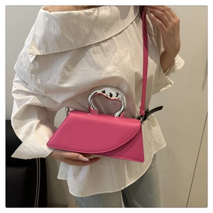 Detail of rose pink handbag featuring asymmetrical geometric flap and silver metal handle