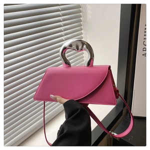 Close-up of pink geometric handbag with fluid silver metal handle and matte leather texture