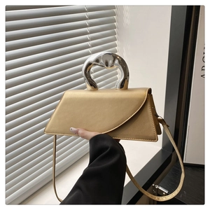 Detail of champagne gold trapezoid bag with artistic chrome sculptural handle and slim strap