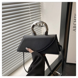 Detail of minimalist black leather handbag with artistic silver liquid metal handle
