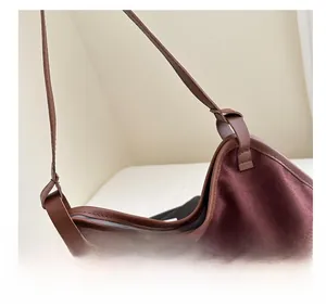 Detailansicht aus dunkelburgunderrotem Wildleder mit braunem Ledergriff und Knotendetail