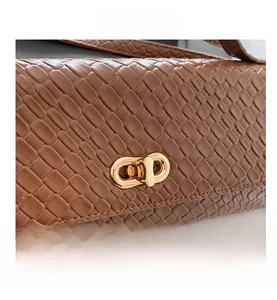 Détail d'un sac à main marron à texture tressée avec un fermoir tournant en métal doré