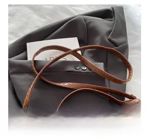 Détail du sac bandoulière marron tressé avec sangle réglable et boucle métallique