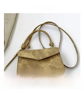 Close-up of olive brown textured handbag with gold hardware and top handle detail