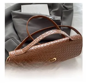 Gros plan du sac à main en cuir marron gaufré croco avec fermoir doré tournant