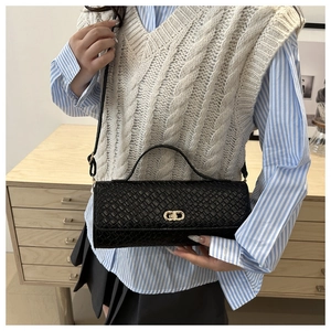 Détail du sac bandoulière tissé noir avec fermoir rotatif ovale doré et fine bandoulière
