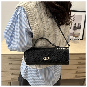 Détail de la texture en cuir noir tressé et de la boucle dorée de ce sac porté épaule chic