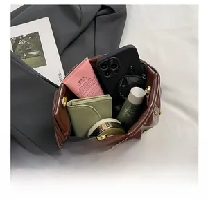 Internal storage view of the brown leather pleated bag with daily essentials inside