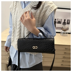 Gros plan du sac en cuir tressé noir avec fermoir en métal doré et texture riche