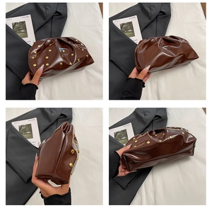 Macro detail of brown patent leather pleated bag with golden cylindrical rivet accents