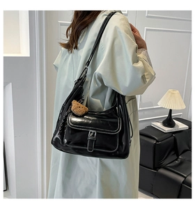Detail of black tote bag with white contrast stitching and a cute bear charm