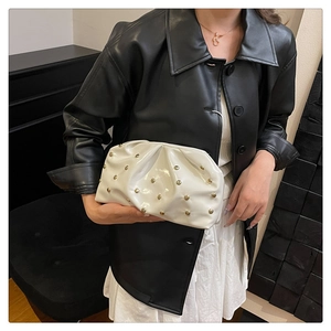 Detail of white pleated cloud bag featuring glossy patent leather and gold metal studs