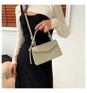 Detail of light green leather satchel showing envelope flap and golden hardware accents