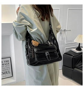 Detail of black glossy tote bag with white contrast stitching and plush bear charm