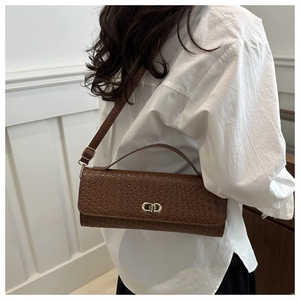 Détail du sac texturé tissé marron foncé avec boucle métallique CD dorée sur la bandoulière