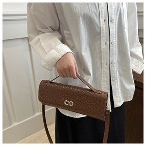 Détail de la texture tressée marron du petit sac carré avec fermoir ovale en métal doré