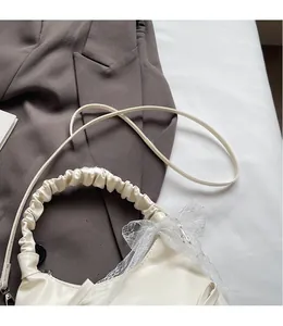 Detail of white cloud bag featuring delicate lace bow and adjustable smooth shoulder strap