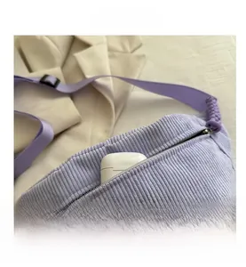 Detail view of purple corduroy fanny pack showing zip closure and headphone storage space