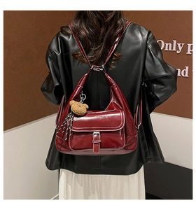 Detail of dark red high-gloss leather backpack with bear charm and front flap pocket