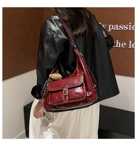Detail of burgundy PU leather hobo bag featuring contrast white stitching and bear charm