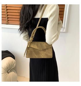 Detail of minimalist khaki leather handbag with unique knotted handle and shoulder strap
