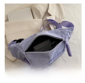Macro view of purple corduroy fanny pack showing interior storage space and metal zipper