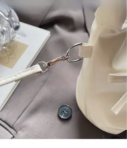 Detail of silver metal swivel hook and D-ring on cream bow shoulder bag strap