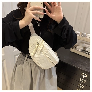 Detail of cream corduroy waist bag showing ribbed texture and woven zipper pullers