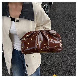 Detail of dark brown patent leather clutch with gold studs and pleated cloud design