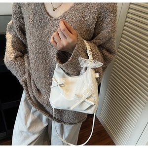 Close-up of white pleated cloud bag with lace bow decoration and slender strap