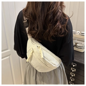 Detail of off-white corduroy waist bag with braided zipper pulls and adjustable strap