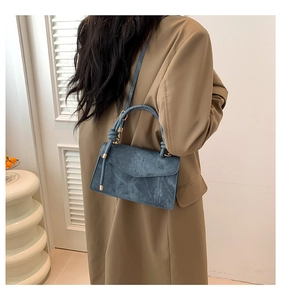 Detail showing vintage textured dark blue leather bag with elegant knot handle and gold hardware